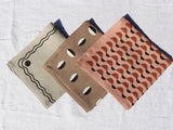 Set of three neutral linen napkins featuring different geometric patterns